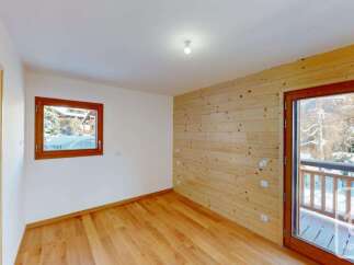 Experience cozy living in this charming room featuring warm wooden paneling and a large window offering picturesque snowy views.
