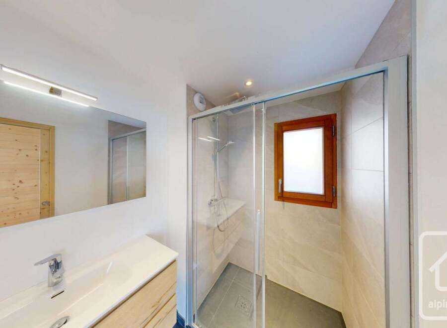 This modern bathroom features a sleek vanity with a vessel sink and a chrome faucet, complemented by a large mirror with integrated lighting.