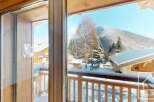 Experience the charm of a winter wonderland from this property's balcony, offering breathtaking views of snow-capped mountains and evergreen trees.
