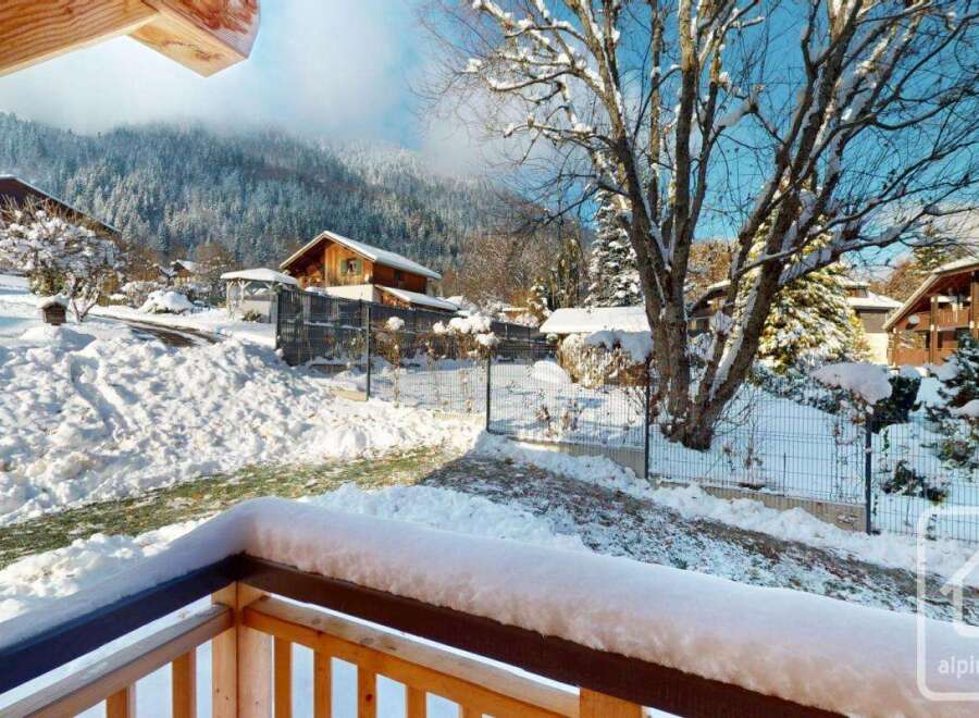 Experience the charm of a winter wonderland from this property's balcony, offering stunning views of snow-covered mountains and traditional chalets.