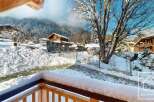 Experience the charm of a winter wonderland from this property's balcony, offering stunning views of snow-covered mountains and traditional chalets.