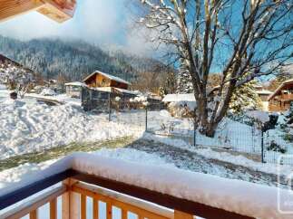 Experience the charm of a winter wonderland from this property's balcony, offering stunning views of snow-covered mountains and traditional chalets.