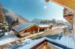 Experience the charm of a winter wonderland with these stunning wooden chalets nestled in a snowy mountain landscape.