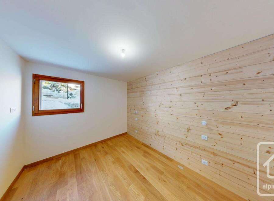 Experience the charm of this room featuring warm, natural wood paneling on one wall and a pristine white ceiling.