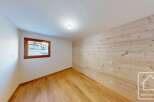 Experience the charm of this room featuring warm, natural wood paneling on one wall and a pristine white ceiling.