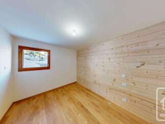 Experience the charm of this room featuring warm, natural wood paneling on one wall and a pristine white ceiling.