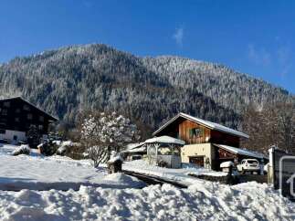 Experience the charm of a winter wonderland with this picturesque property nestled against a snow-covered mountain.