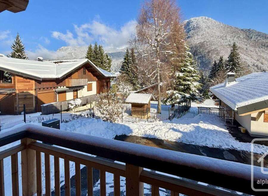 Experience the charm of a winter wonderland from this property's balcony, offering stunning views of snow-covered chalets and majestic mountains.