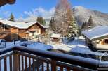Experience the charm of a winter wonderland from this property's balcony, offering stunning views of snow-covered chalets and majestic mountains.