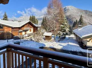 Experience the charm of a winter wonderland from this property's balcony, offering stunning views of snow-covered chalets and majestic mountains.