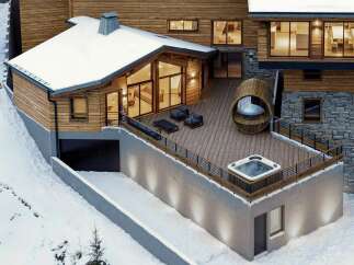 Experience luxury mountain living in this stunning chalet, featuring a spacious wooden deck with a relaxing hot tub and unique barrel-shaped seating area.