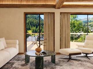 Experience luxury mountain living in this stunning living room, featuring a plush sofa and a comfortable armchair with an ottoman, perfect for relaxing.