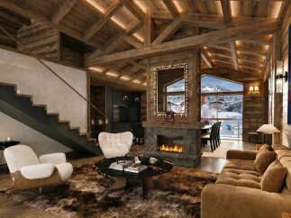 Experience ultimate luxury in this stunning mountain chalet, featuring a grand stone fireplace and exposed wooden beams that create a warm, inviting atmosphere.