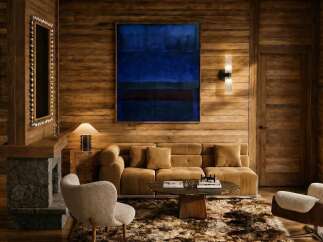 Experience luxury mountain living in this stunning chalet, featuring a cozy stone fireplace and rich wood paneling throughout.