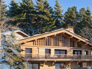 Experience luxury mountain living in this stunning chalet, nestled amidst snow-dusted pine trees.