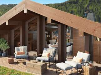 Experience luxury mountain living with this stunning chalet-style home featuring expansive wooden decks and panoramic views of lush green forests.