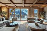 Experience luxury mountain living in this stunning chalet, featuring a spacious living area with a curved sofa and plush seating, perfect for cozy evenings.