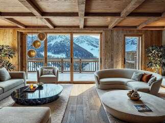 Experience luxury mountain living in this stunning chalet, featuring a spacious living area with a curved sofa and plush seating, perfect for cozy evenings.