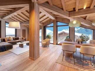 Experience luxury mountain living in this stunning chalet featuring a spacious open-plan living area with a plush sectional sofa and a modern dining set.