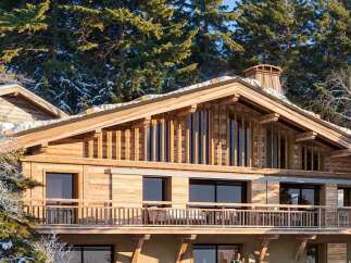 Experience luxury mountain living in this stunning wooden chalet, nestled amidst snow-dusted pine trees.