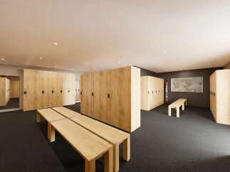 Discover this modern locker room, featuring light wood lockers with black hardware and ample seating.