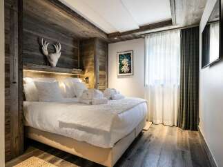 Experience rustic luxury in this beautifully appointed bedroom, featuring a plush king-sized bed adorned with crisp white linens and fluffy pillows.