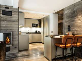 Experience cozy living in this modern mountain retreat, featuring a stunning wood-paneled fireplace and a sleek, integrated kitchen.