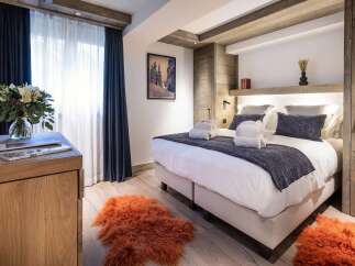 Experience luxury mountain living in this beautifully appointed bedroom, featuring a plush king-size bed adorned with soft linens and decorative pillows.