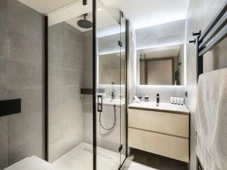 Experience modern luxury in this sleek bathroom, featuring a spacious walk-in shower with a rainfall showerhead and elegant grey tiling.