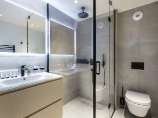 This modern bathroom features a sleek vanity with a vessel sink and a large, illuminated mirror.