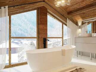 Experience luxury mountain living in this stunning bathroom featuring a freestanding soaking tub with breathtaking panoramic views of the snowy landscape.