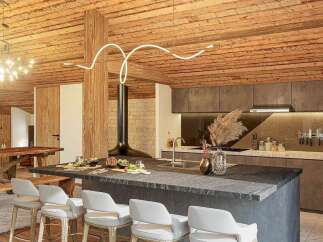 Experience luxury mountain living in this stunning chalet kitchen, featuring a sleek island with bar seating and a modern fireplace.
