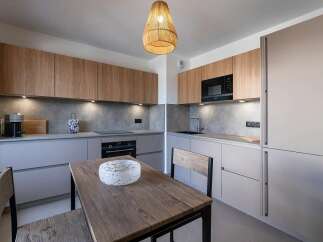 Experience modern living in this sleek kitchen featuring warm wood cabinetry contrasted with cool grey countertops and backsplash.