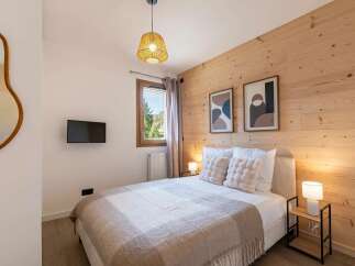 Experience cozy mountain living in this charming bedroom featuring a comfortable bed adorned with plush pillows and a warm throw blanket.