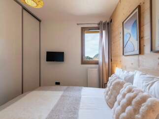 Experience cozy mountain living in this charming bedroom featuring a comfortable bed adorned with plush pillows and a soft throw blanket.