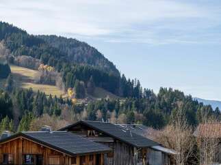Experience the charm of alpine living with these rustic wooden chalets nestled against a backdrop of lush green forests and rolling hills.