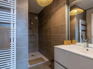 This modern bathroom features a sleek white vanity with a built-in sink, complemented by a large mirror reflecting a stylish woven pendant light.