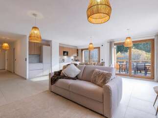 Experience modern living in this spacious apartment, featuring a comfortable living area with a plush sofa and decorative pillows, perfect for relaxation.