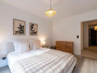 This beautifully appointed bedroom features a comfortable queen-size bed adorned with plush pillows and a cozy checkered throw blanket.