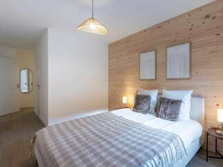 Experience cozy living in this charming bedroom featuring a plush bed adorned with a checkered throw and soft pillows.