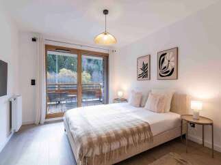 Experience comfort and style in this beautifully appointed bedroom, featuring a plush queen-size bed adorned with soft, decorative pillows and a cozy throw blanket.