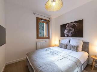 Experience comfort and style in this beautifully appointed bedroom, featuring a plush king-sized bed adorned with crisp white linens and two decorative fur pillows.