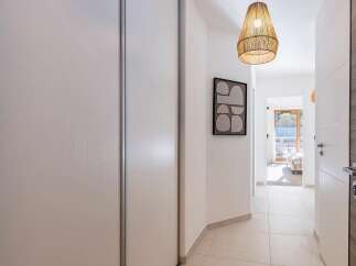Step into this inviting hallway, featuring a large white wardrobe for ample storage and a striking abstract art piece on the wall.