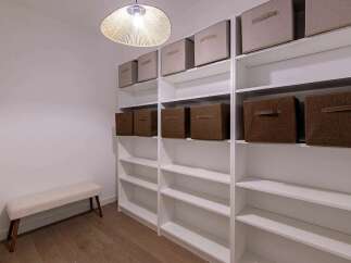 Discover ample storage solutions in this spacious walk-in closet, featuring extensive white shelving units perfect for organizing clothes and accessories.