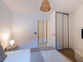 This bedroom offers a serene and modern retreat, featuring a comfortable bed adorned with plush pillows and a cozy throw.