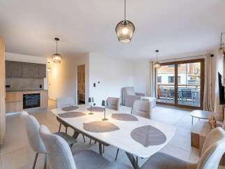 This modern apartment features a spacious open-plan living area with a dining table seating six and a well-equipped kitchen.