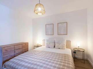 This inviting bedroom features a comfortable queen-size bed adorned with plush pillows and a cozy plaid throw.