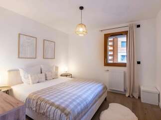 Experience comfort and style in this beautifully appointed bedroom, featuring a plush king-sized bed adorned with a cozy plaid throw.