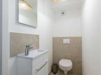 This modern bathroom features a sleek white vanity with a chrome faucet, complemented by a textured tile backsplash.