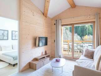 Experience cozy living in this charming wooden cabin, featuring a spacious living area with a comfortable sofa and a modern entertainment center.